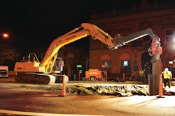 A LiuGong 936D excavator drives an I-beam into the ground to install trench box walls prior to pipeline replacement.
