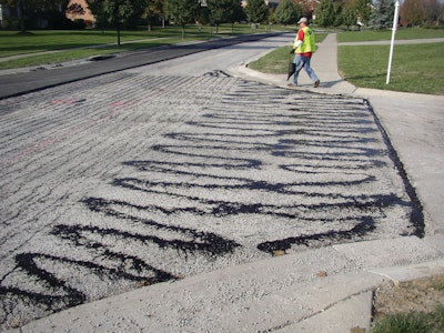 Improper application of tack coats, like this tack that was applied by hand using a pour bucket, eliminates any benefits that can result from using tack coats to improve paving.