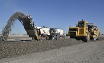Instead of five to six haul trucks recirculating, Las Vegas Paving uses two paddle wheel scrapers to pick up windrows of RAP and deposit the material on airfield unpaved areas, where it will be compacted and used for erosion control.
