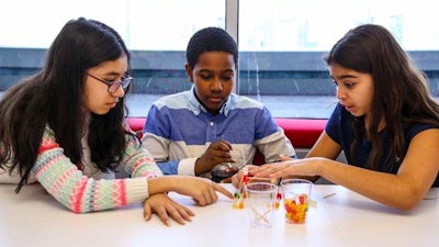 Middle school students from DREAM work together to build a tower using gummy bears and toothpicks.