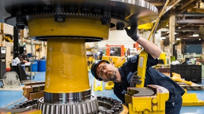 Komatsu employee at the Peoria, Ill., plant inspects an electric dump truck component. Komatsu has 28 U.S. manufacturing facilities that produce construction, mining, forklift and forestry equipment.