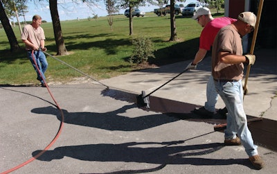 Use a brush and squeegee to spread the sealcoat out on the pavement