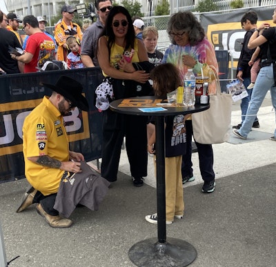 DIGatron Driver Tristan England signs autographs in the JCB booth during the pit party.