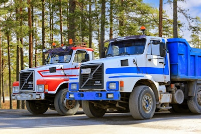 Heavy-duty trucks on asphalt yard.