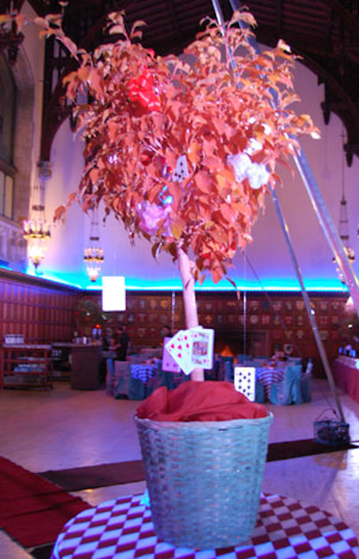 At the Palais d'Hiver event, black-and-white checkered linens topped tables, and teapots and teacups held floral arrangements. Giant playing cards also hung from potted plants.