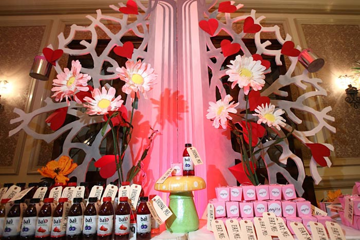 Syzygy Event Productions worked with Digital Lightning to turn the reception and ballroom areas into a whimsical environment. A large, white tree decorated with red hearts inspired by the story's Red Queen served as the backdrop for the check-in desk.