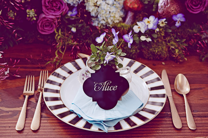 For an Alice in Wonderland-inspired design inspiration shoot, Kate Miller Events displayed Luxecuts custom laser-cut place cards leaning against vintage teacups filled with flowers at each place setting.