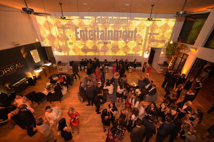 For the Entertainment Weekly party, Event Eleven this year removed all the furniture and trees from Fig & Olive's main dining room and added custom cushions and furnishings to the space. The producers also added a projection against the wall of the interior and filled the room with hundreds of candles. Gray sofas with brass end tables and touches of navy blue decorated the space.