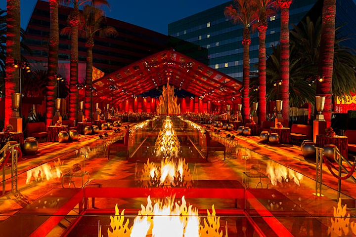Real fire was also a decorative element at the party: 24-foot-long reflecting ponds showcased multiple flaming sculptures. Inside the 120- by 100-foot dining pavilion, guests ate fare provided by Wolfgang Puck, such as burrata and peach salad, New York steak, and doughnut bread pudding.