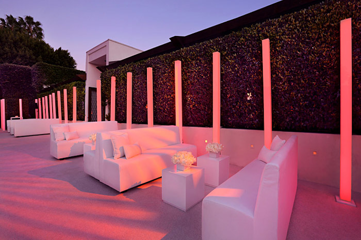 Custom monochromatic white seating arrangements complemented the LED tubes. Roses in modern containers topped tables alongside votive candles—all white.