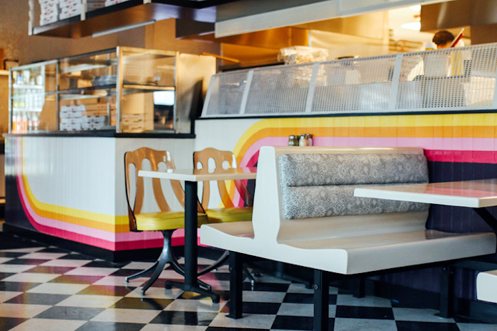 Austin’s popular New York-style pizzeria Home Slice opened its second location in the North Loop neighborhood in late May. Unlike the original Home Slice, the new restaurant’s space features both dine-in and take-out menus. The space’s eclectic 1970s- and 1980s-inspired decor features chandeliers made with grape swag light fixtures, brass peacock screens, red upholstered booths and banquettes, and vintage gilt mirrors. There’s a patio as well, both indoor and outdoor bar seating, and a quirky outdoor play area with hilly AstroTurf and tunnels. Along with the concept's beloved pizza and subs, the new restaurant includes its first full bar with cocktails.