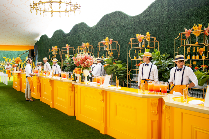 The 12th annual Veuve Clicquot Polo Classic took place June 1 at Liberty State Park. The event featured a bar painted in the champagne brand’s yellow-orange color, backed by a hedge wall decorated with champagne bottles and a variety of orange, yellow, and red flowers. Servers wore branded hats and orange aprons. Veuve Clicquot partnered with Overland Entertainment to design the event.