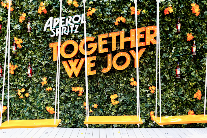 Guests could pose for photos on orange swings in front of a step-and-repeat, which featured orange flowers and a marquee-style sign that read “Together We Joy.”