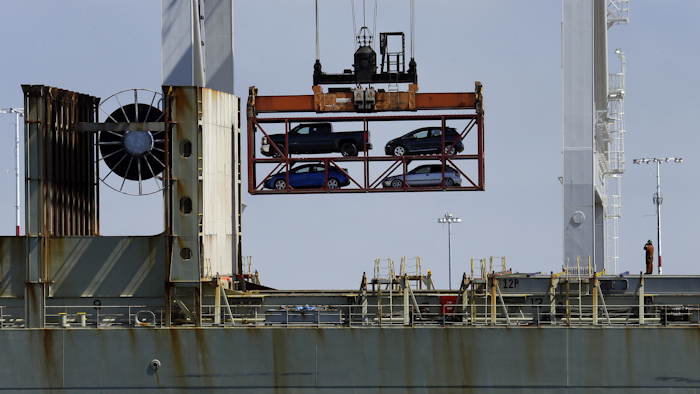 In this July 13, 2017 file photo, a crane transporting vehicles operates on a container ship at the Port of Oakland, in Oakland, Calif. A key draw for foreign assembly plants and investment has been Mexico's low wages. With many workers unable to afford the vehicles Mexico produces, the country exports about three times as many cars as are purchased domestically, most to the United States. (AP Photo/Ben Margot, File)