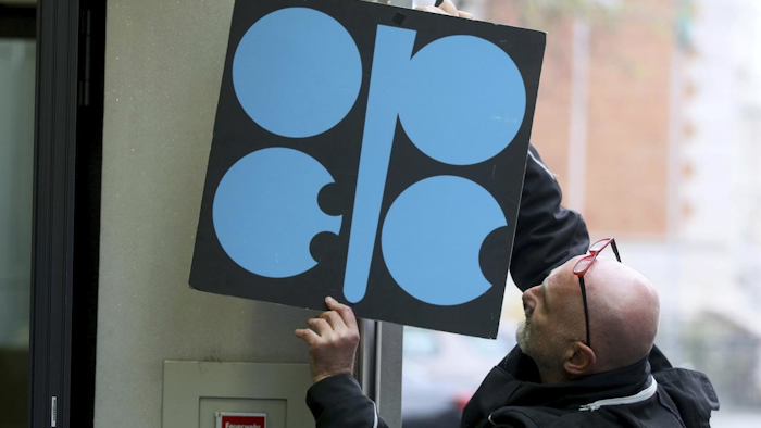 A worker attaches a poster of the Organization of the Petroleum Exporting Countries, OPEC, at their headquarters in Vienna, Austria, Wednesday, Nov. 29, 2017. With bills rising for gasoline or heating oil, consumers around the world are paying the price for a decision by OPEC and Russia last year to cut production. The strategy is working for those oil-producing nations and will likely be extended at a meeting Thursday. (AP Photo/Ronald Zak)
