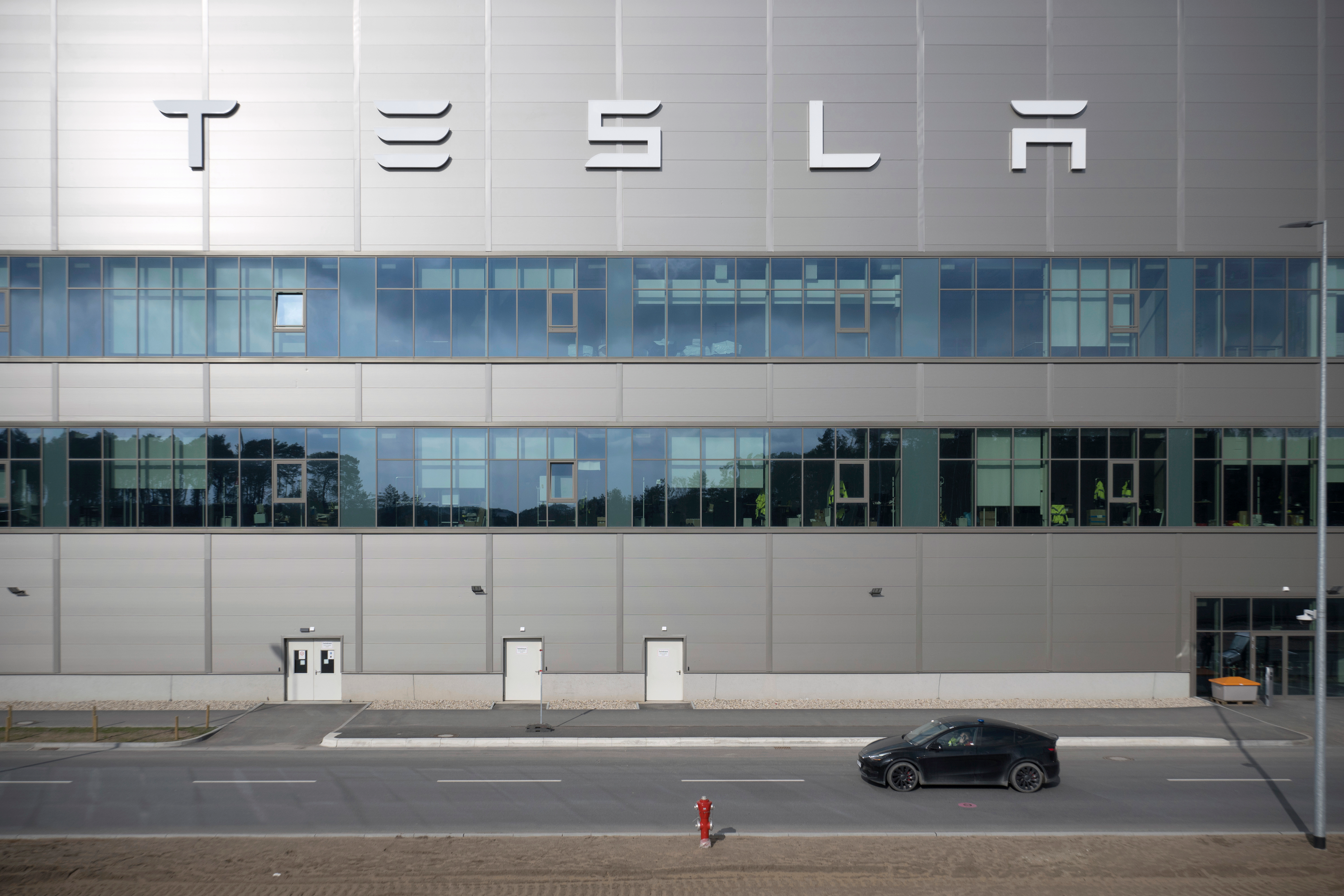 A vehicle from the security service drives by the Tesla car factory after production came to a standstill and workers were evacuated following a power outage, in Gr&uuml;nheide, Germany, Tuesday, March 5, 2024.