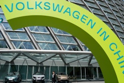 A woman walks past cars on display at a Volkswagen event ahead of the auto show in Beijing, Wednesday, April 24, 2024.