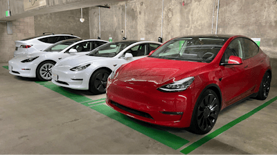 This photo provided by Edmunds shows a line of parked Tesla Model 3 and Model Y vehicles.
