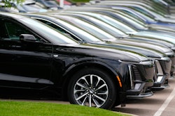 Vehicles sit in a row outside a dealership.