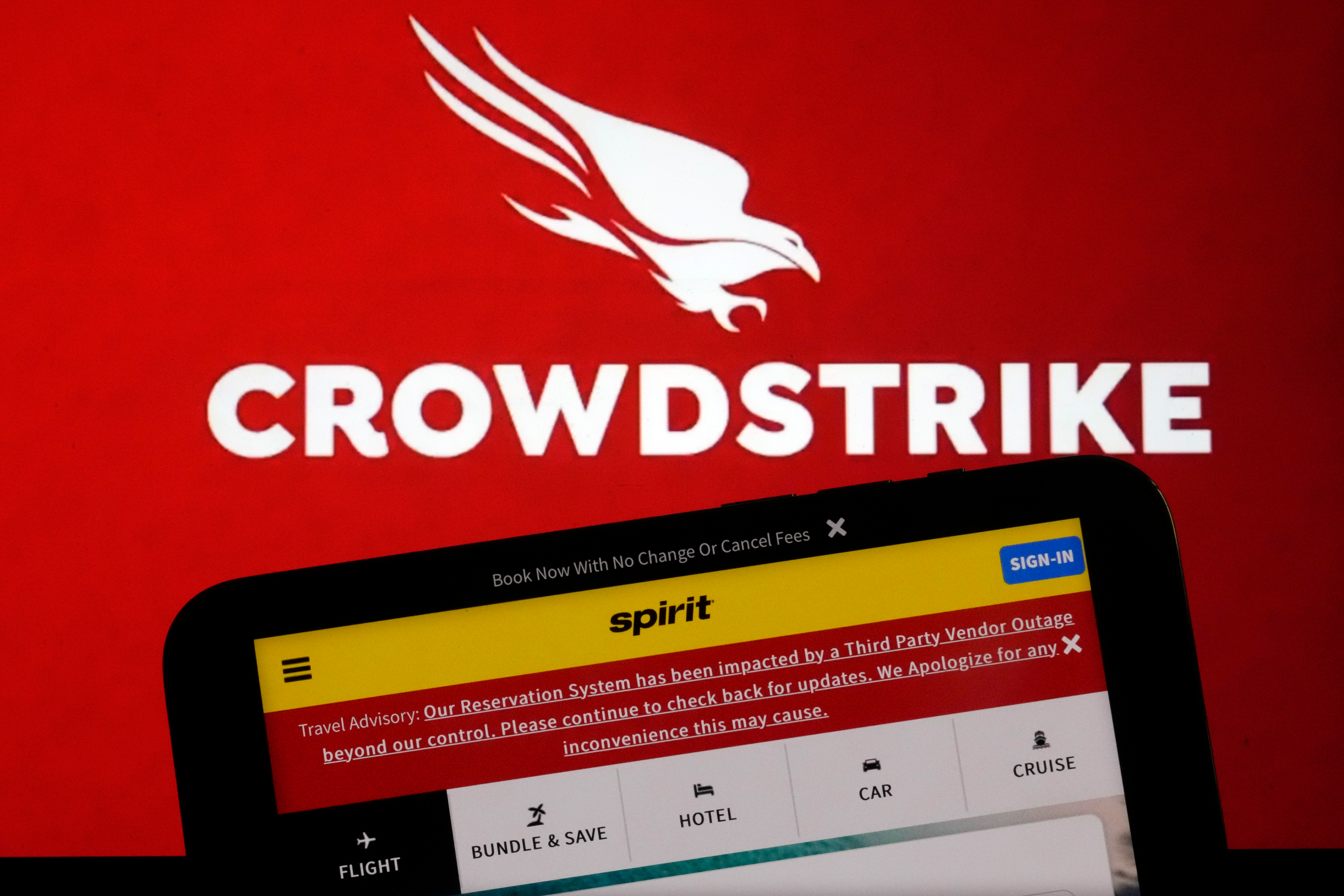 The logo for CrowdStrike and a Spirit Airlines webpage are shown on a computer screen and mobile phone screen, in New York.