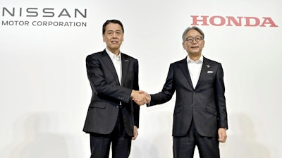 Nissan Chief Executive Makoto Uchida, left, and Honda Chief Executive Toshihiro Mibe shake hands during a joint news conference in Tokyo, Thursday.