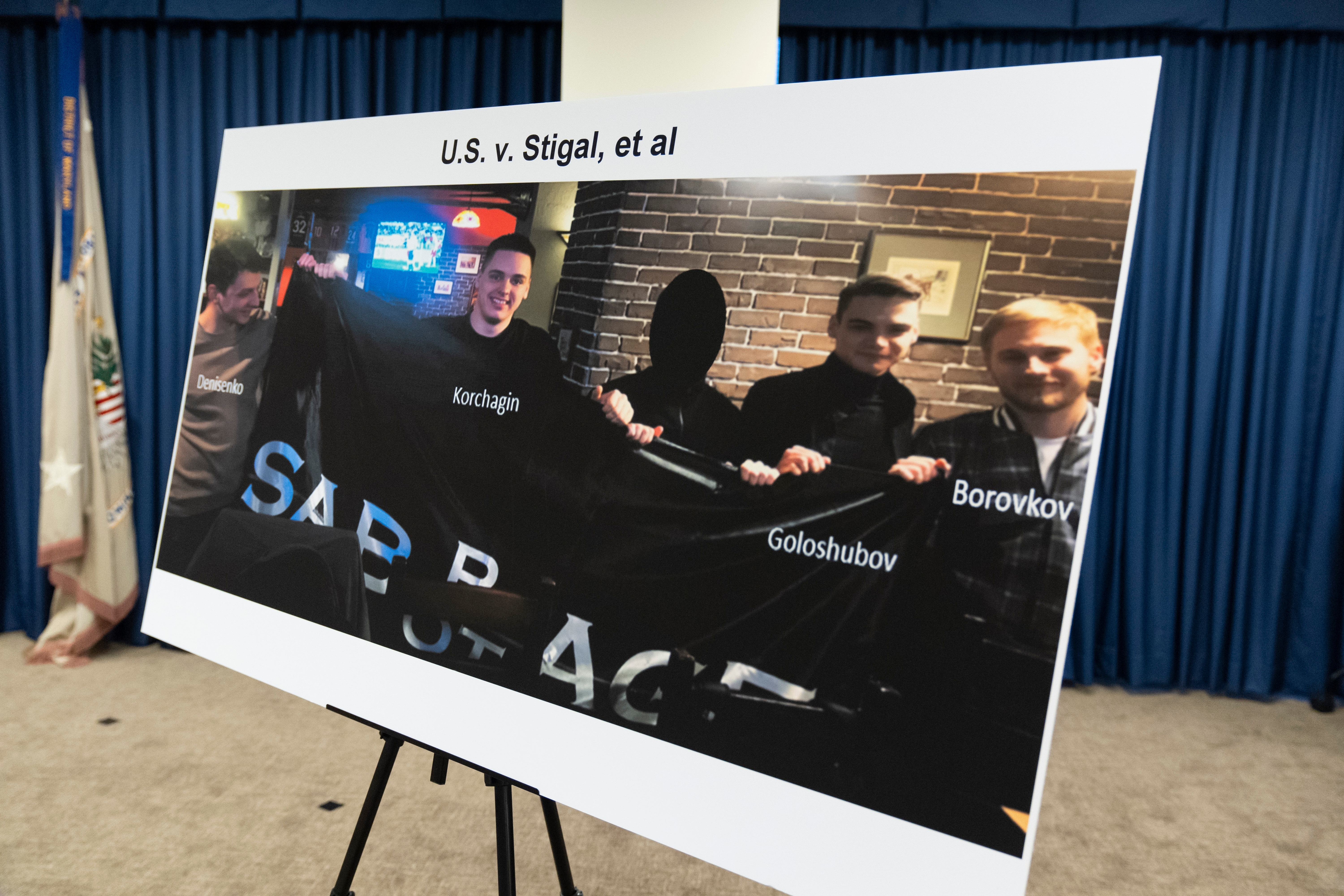 A photo of Russian suspects wanted by the FBI involved in a conspiracy to commit criminal cyber activities against Ukrainian government systems is displayed during a press conference at the Office of the United States Attorney in Baltimore, Thursday, Sept. 5, 2024.