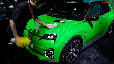 A man cleans a Renault R5 E-TECH car at the Paris Auto Show, in Paris, Monday, Oct. 14, 2024.