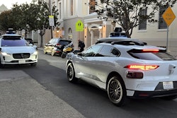 Two Waymo driverless taxis stop before passing one another on a San Francisco street on Feb. 15, 2023.