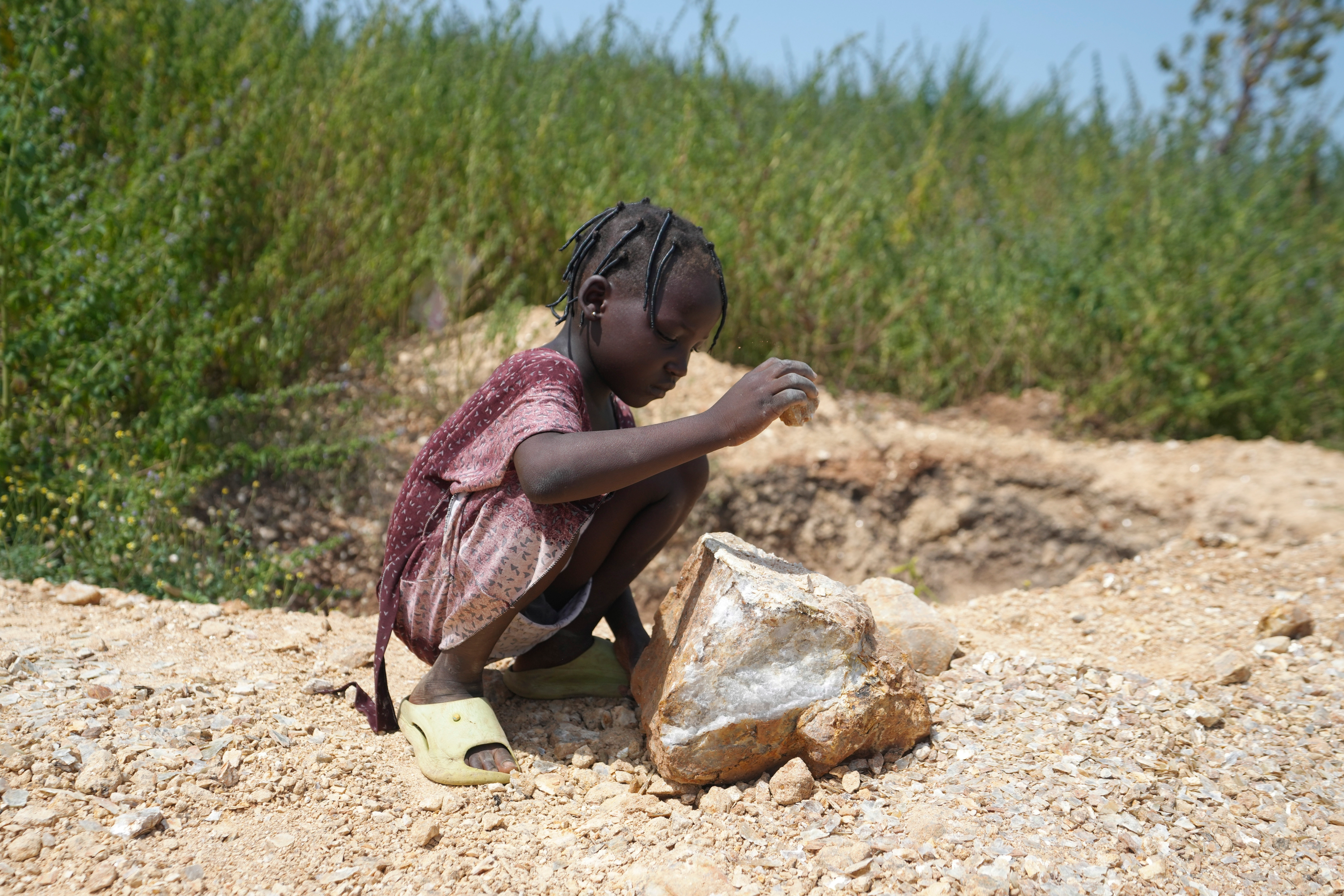 Juliet Samaniya, 6, chips at a rock with a stone tool at an illegal lithium mining site in Paseli, Nigeria, Tuesday, Nov 5, 2024.