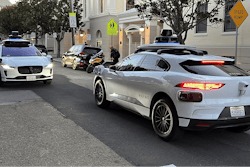 Two Waymo driverless taxis stop before passing one another on a San Francisco street on Feb. 15, 2023.