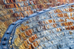 A dump truck convoy travels up through a copper mine.