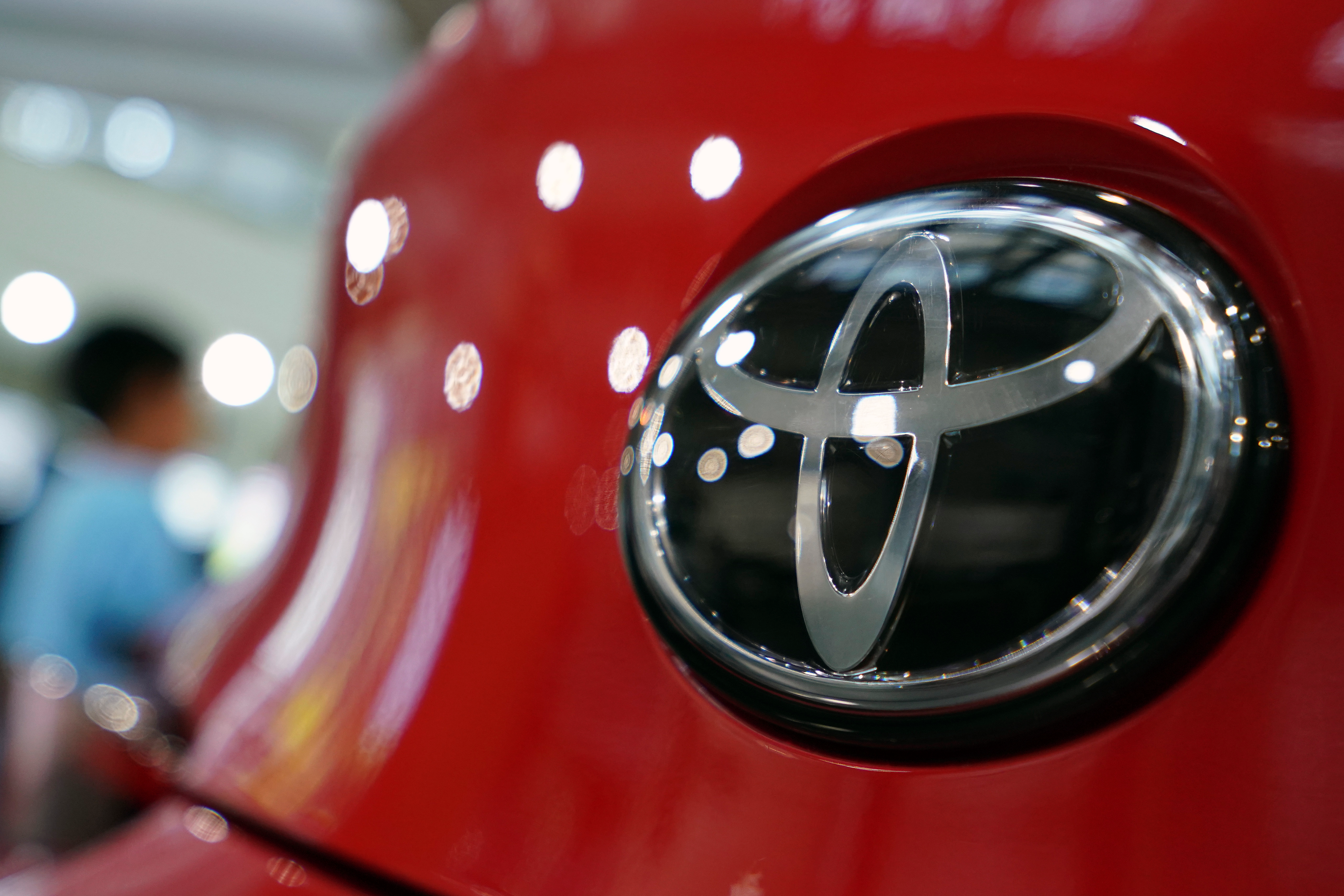 People walk by the logo of Toyota at a show room in Tokyo, Aug. 2, 2019.