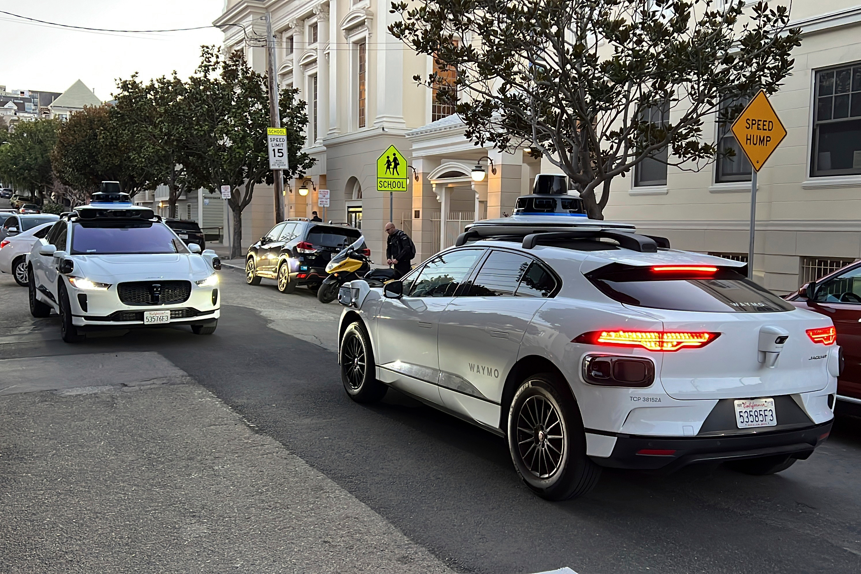 Two Waymo driverless taxis stop before passing one another on a San Francisco street on Feb. 15, 2023.