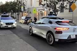 Two Waymo driverless taxis stop before passing one another on a San Francisco street on Feb. 15, 2023.