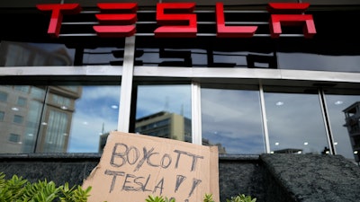 A banner is left outside a Tesla showroom during a demonstration, in Lisbon, Sunday, March 9, 2025.