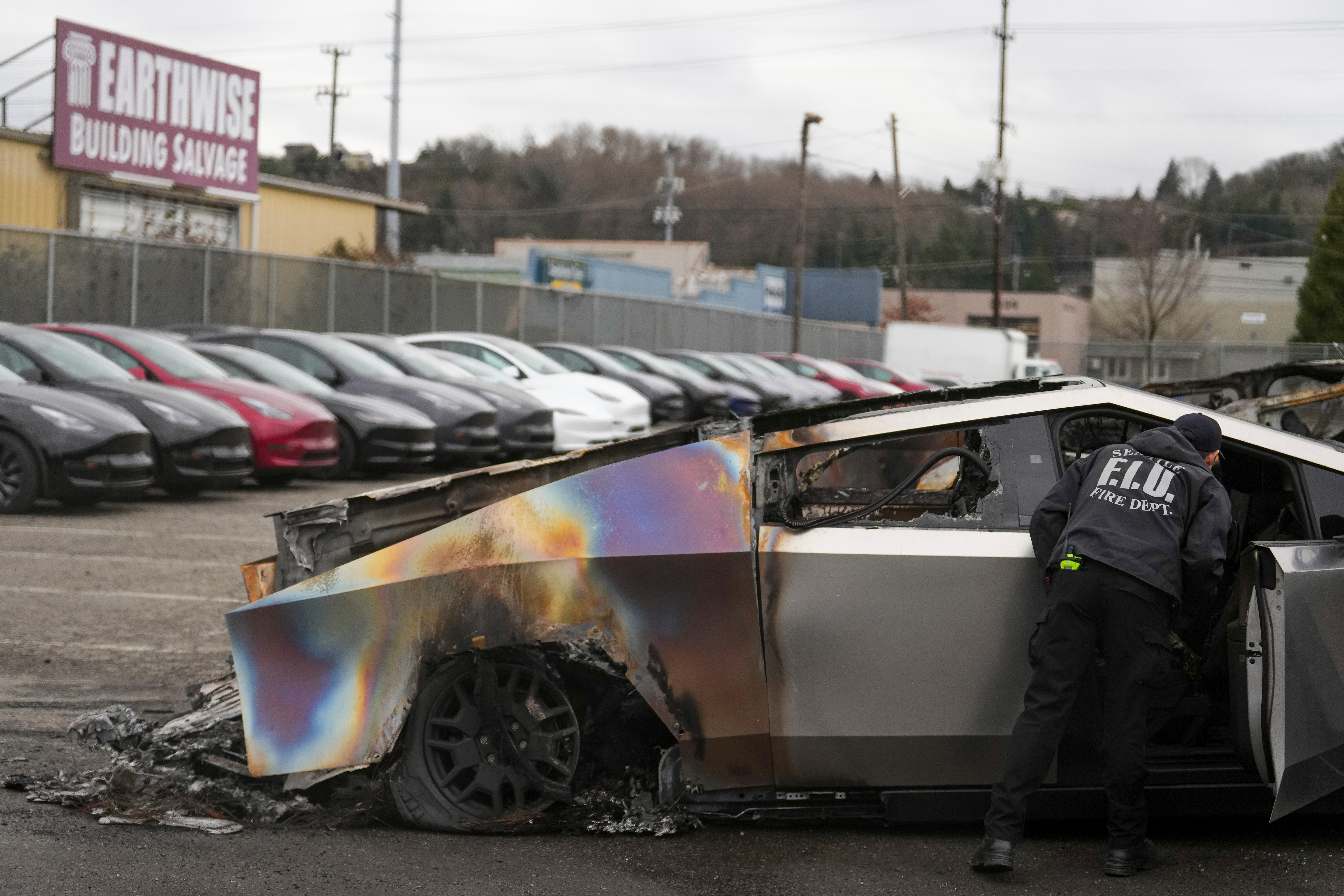 A member of the Seattle Fire Department inspects a burned Tesla Cybertruck at a Tesla lot in Seattle, Monday, March 10, 2025.