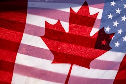 Sunlight shines through the flags of Canada and the United States, held together by a protester outside on Parliament Hill in Ottawa, Feb. 1, 2025.
