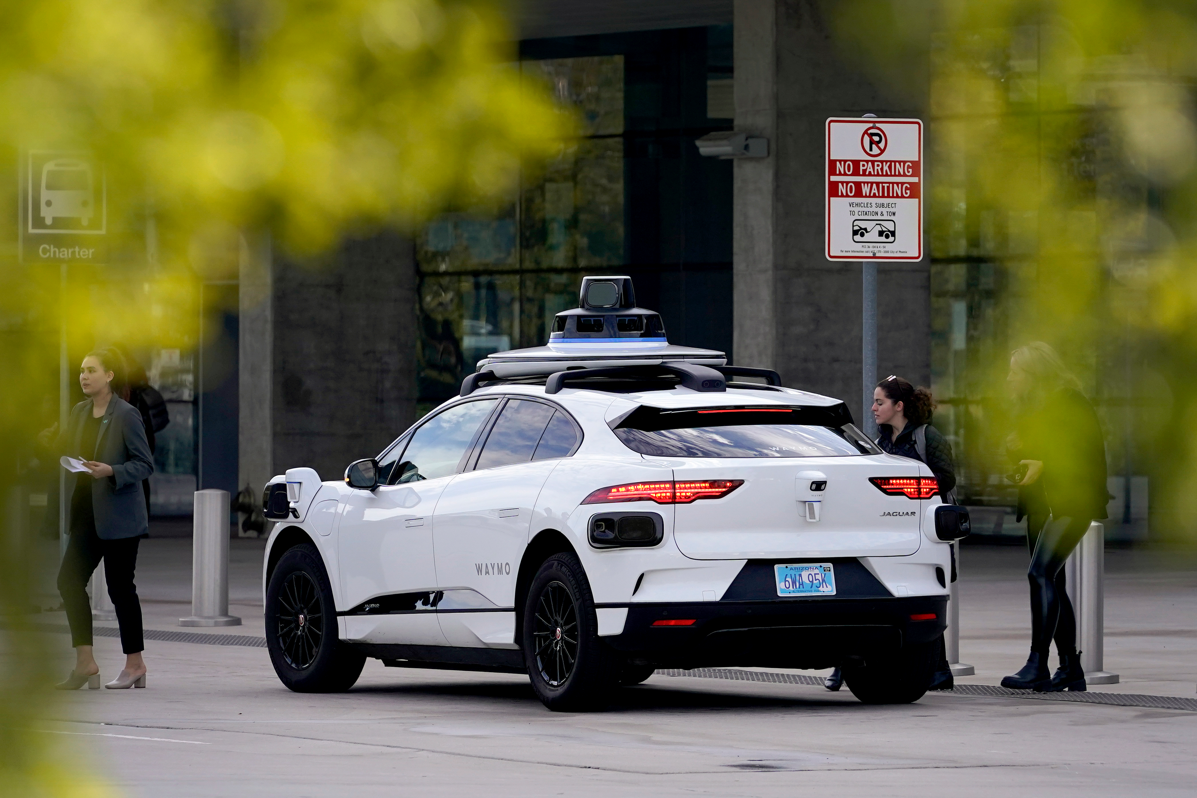 A Waymo self-driving vehicle sits curbside on Dec. 16, 2022, at the Sky Harbor International Airport Sky Train facility in Phoenix.