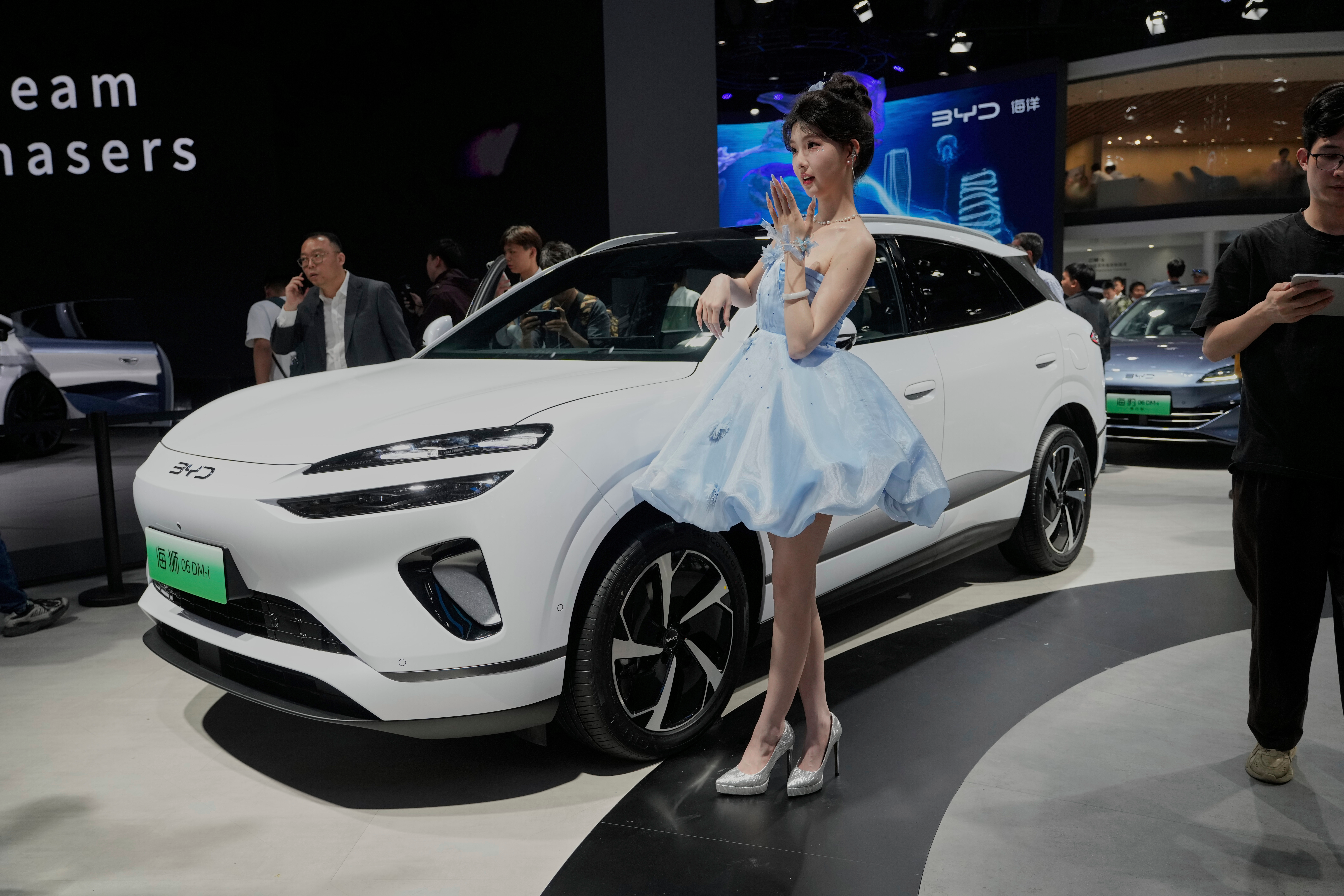 A model poses near the Sea Lion 06 DM-i model from BYD at the Shanghai auto show on Wednesday, April 23, 2025.