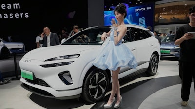 A model poses near the Sea Lion 06 DM-i model from BYD at the Shanghai auto show on Wednesday, April 23, 2025.