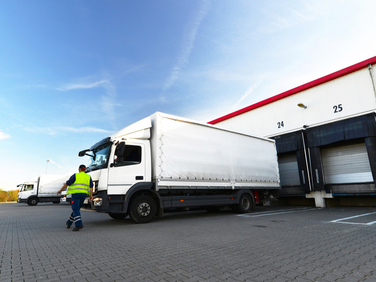 A driver walks toward a truck at a loading dock. Photo: Shutterstock.
