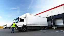 A driver walks toward a truck at a loading dock. Photo: Shutterstock.
