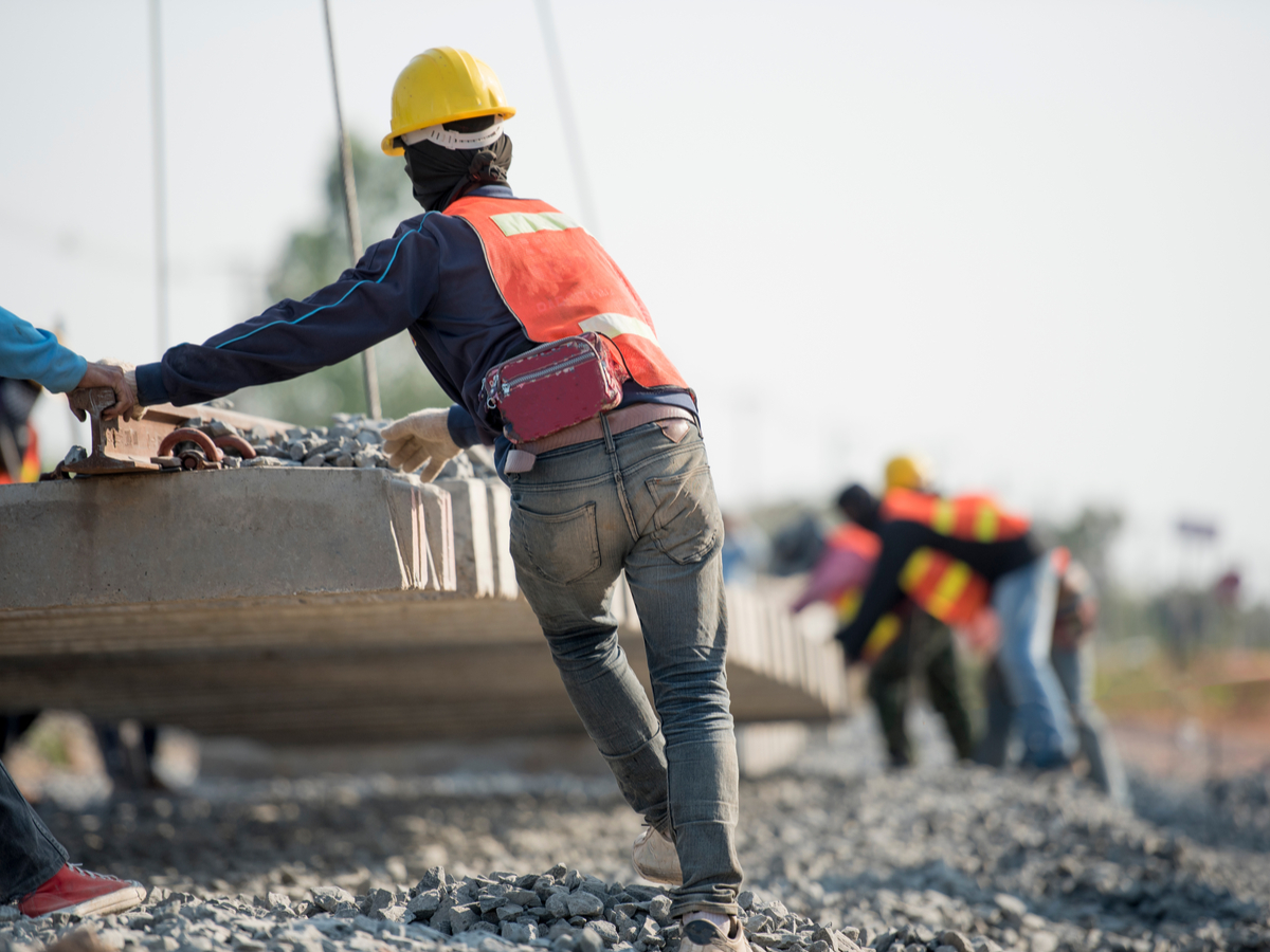 Workers move building materials at a construction site. Photo: Banna Farsai/ Shutterstock.