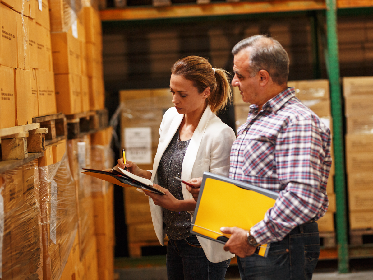 Two workers review documents in a warehouse. Photo: Shutterstock.