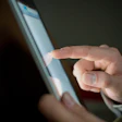 A close-up view of a person touching a digital tablet. Photo: Shutterstock.
