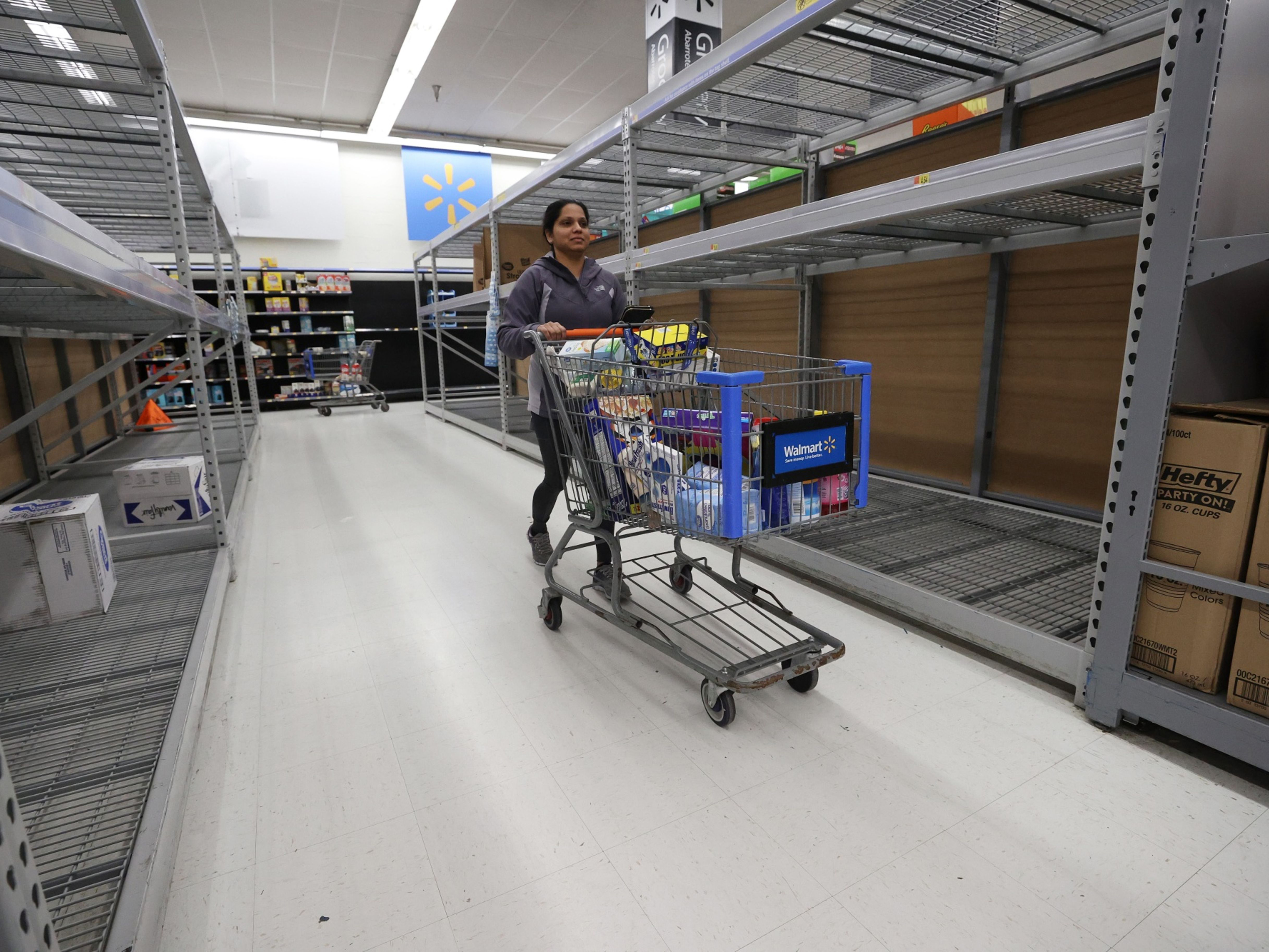 A Walmart Inc. shopper walks by empty shelves. Photo: Bloomberg.