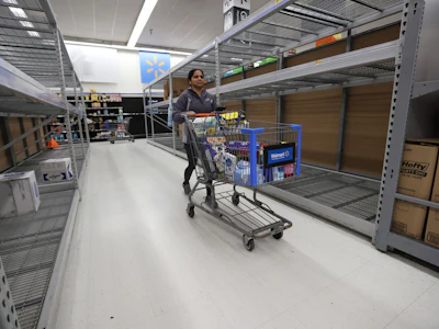 A Walmart Inc. shopper walks by empty shelves. Photo: Bloomberg.