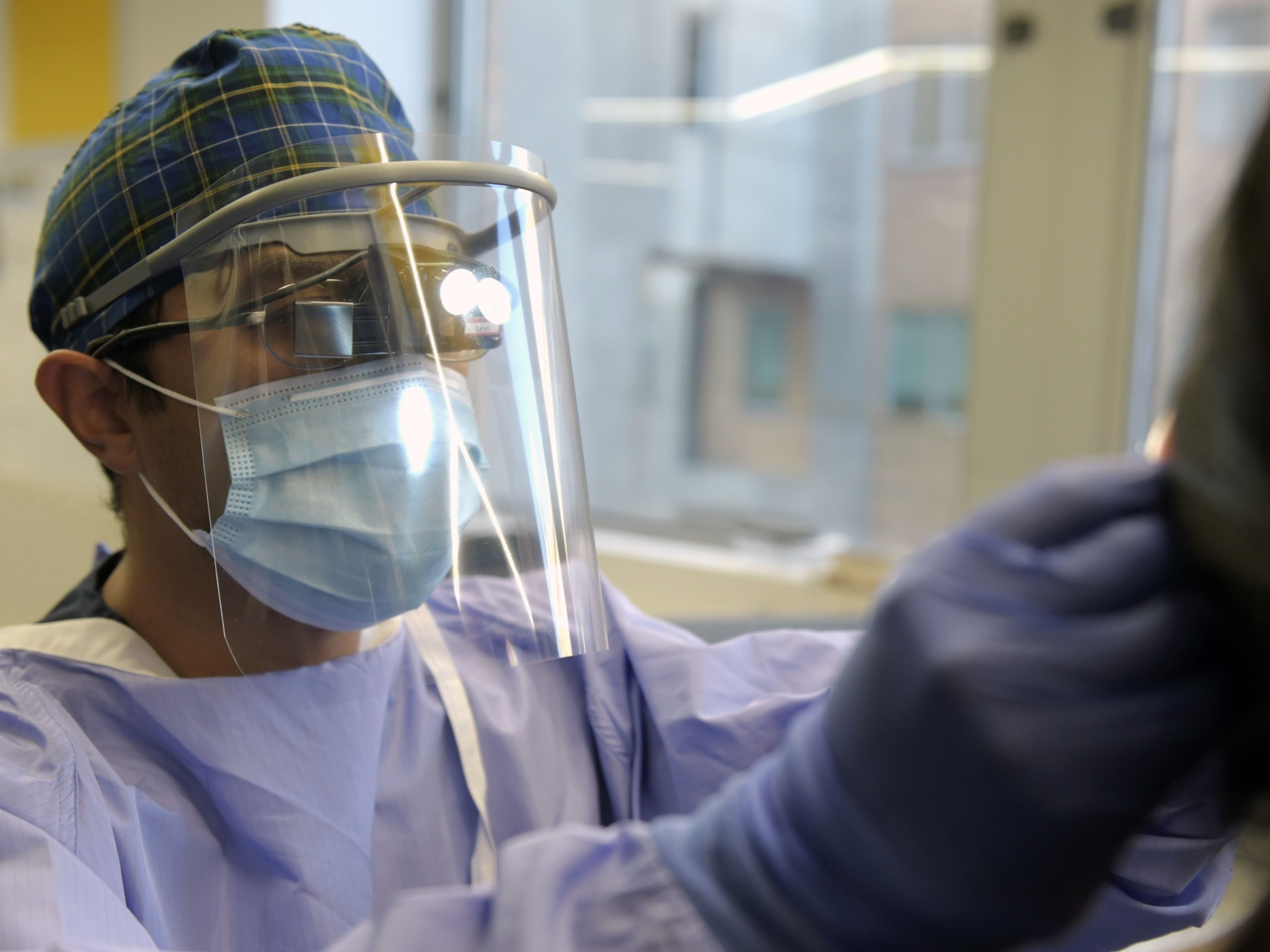 A surgeon wears a 3D printed face shield while inspecting a patient. Photo: Bloomberg.
