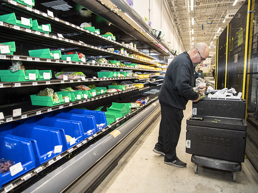 A worker places groceries from an online order into a Peapod delivery bin at a Stop & Shop supermarket. Photo: Bloomberg.