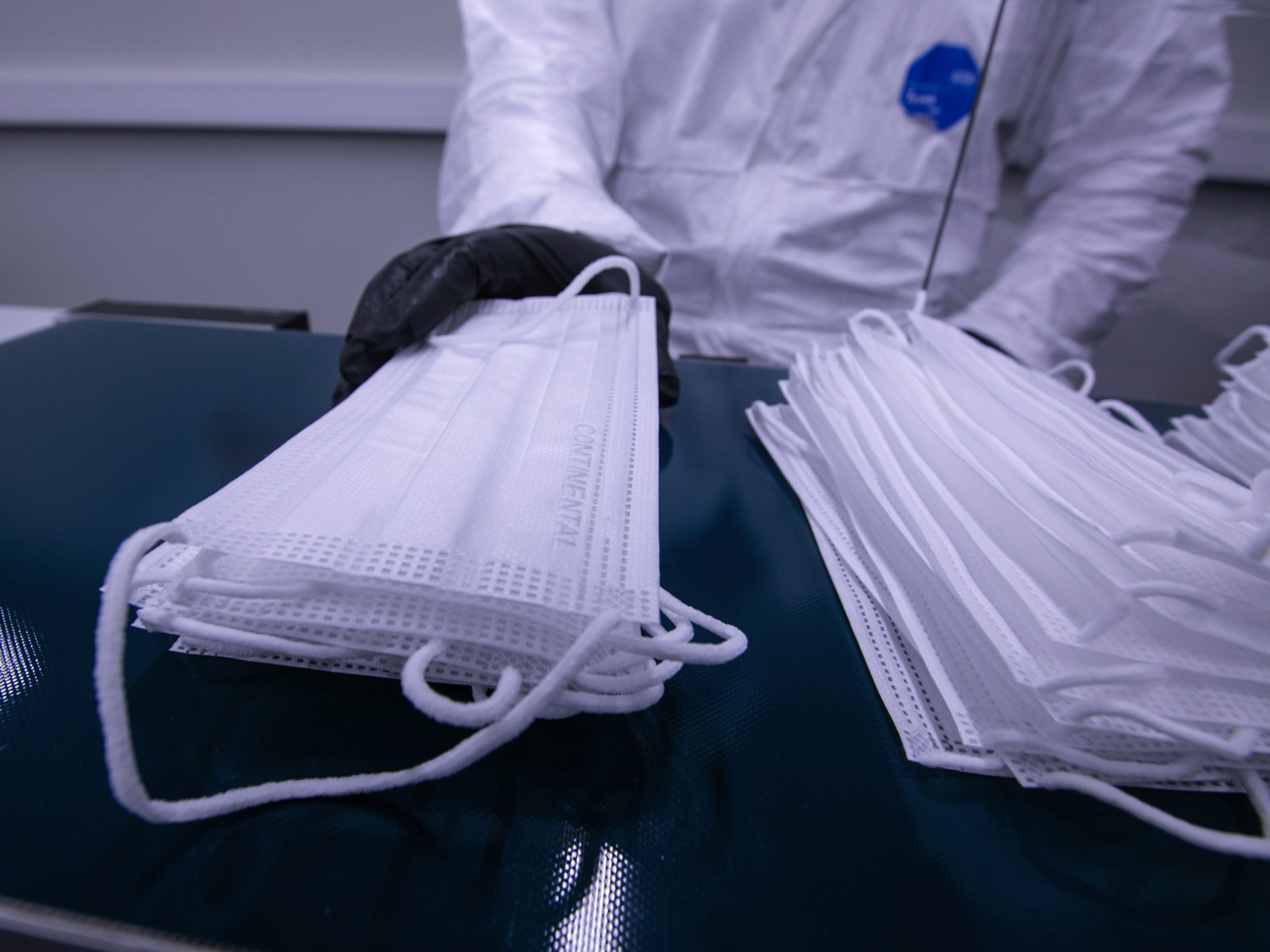 An employee gathers protective face masks from a production line conveyor. Photo: Bloomberg.